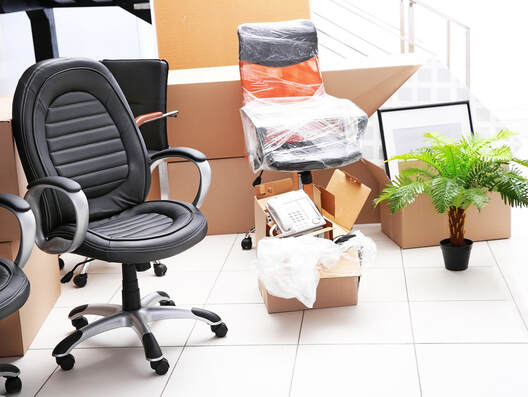 Two office chairs, one of them wrapped. Moving boxes full of office supplies and equipment. 